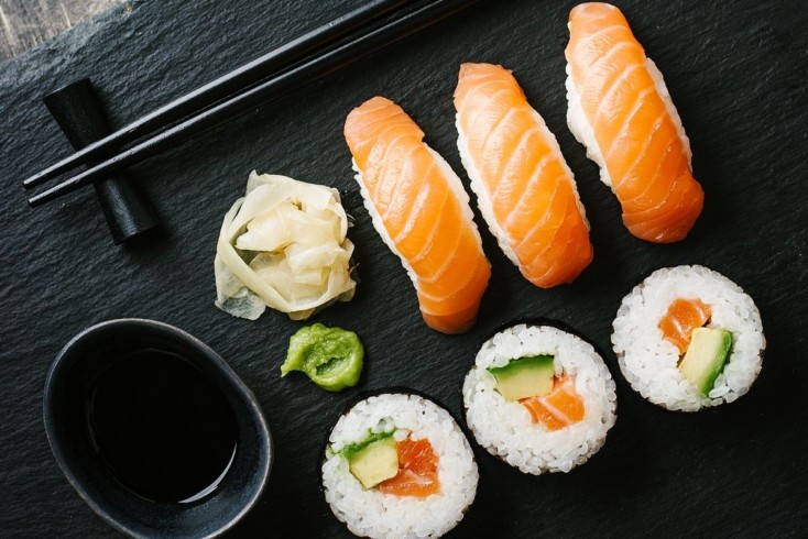 Sushi with avocado and salmon served on plate on dark table. Horizontal with copy space.